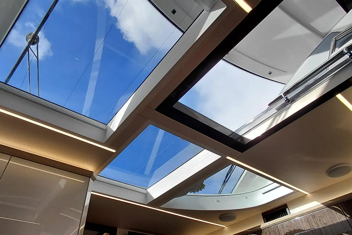 Interior view featuring glass skylights revealing a clear blue sky and white clouds, complemented by modern architectural lighting.